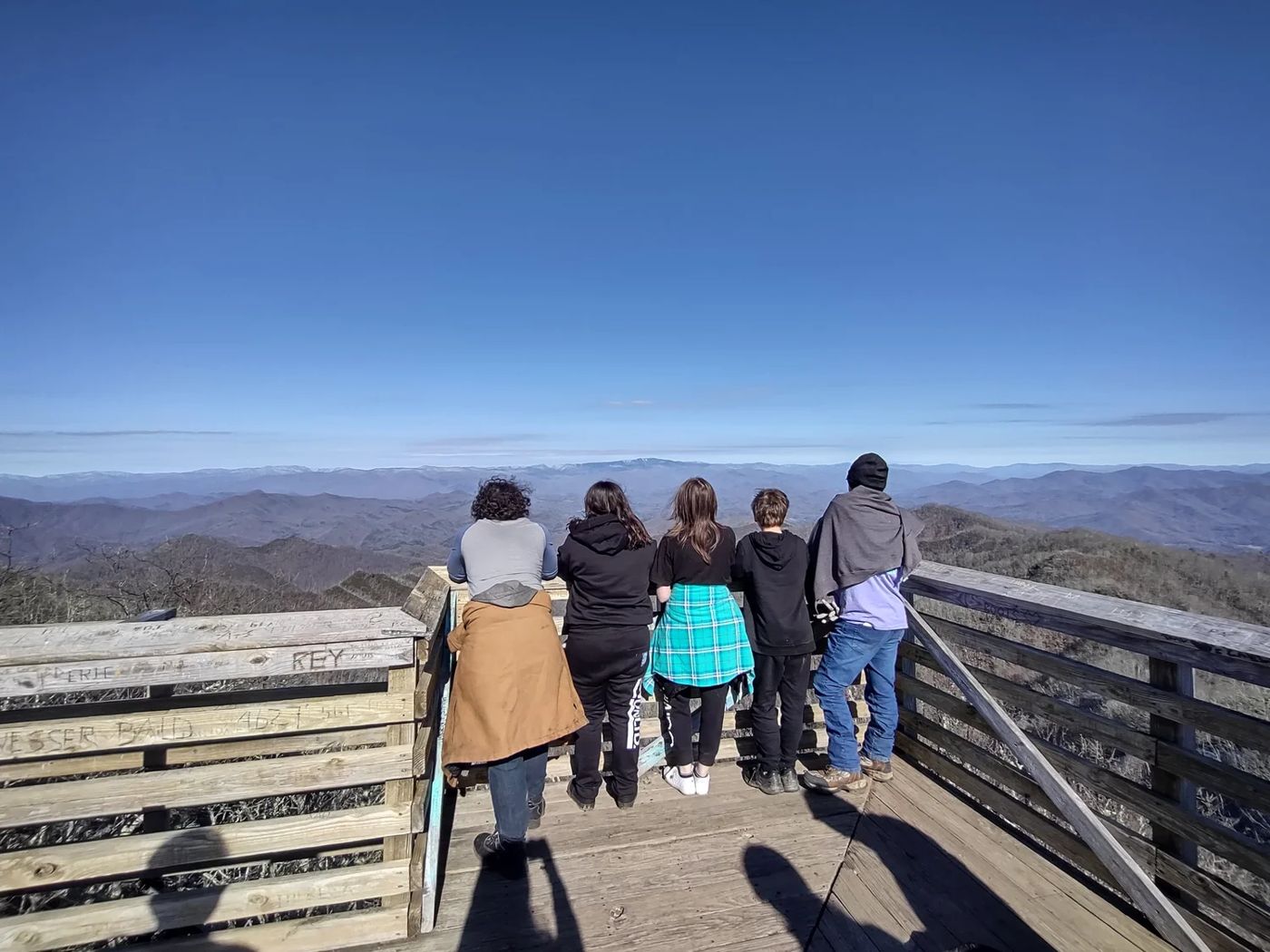 People on a wooden overlook viewing mountain ranges